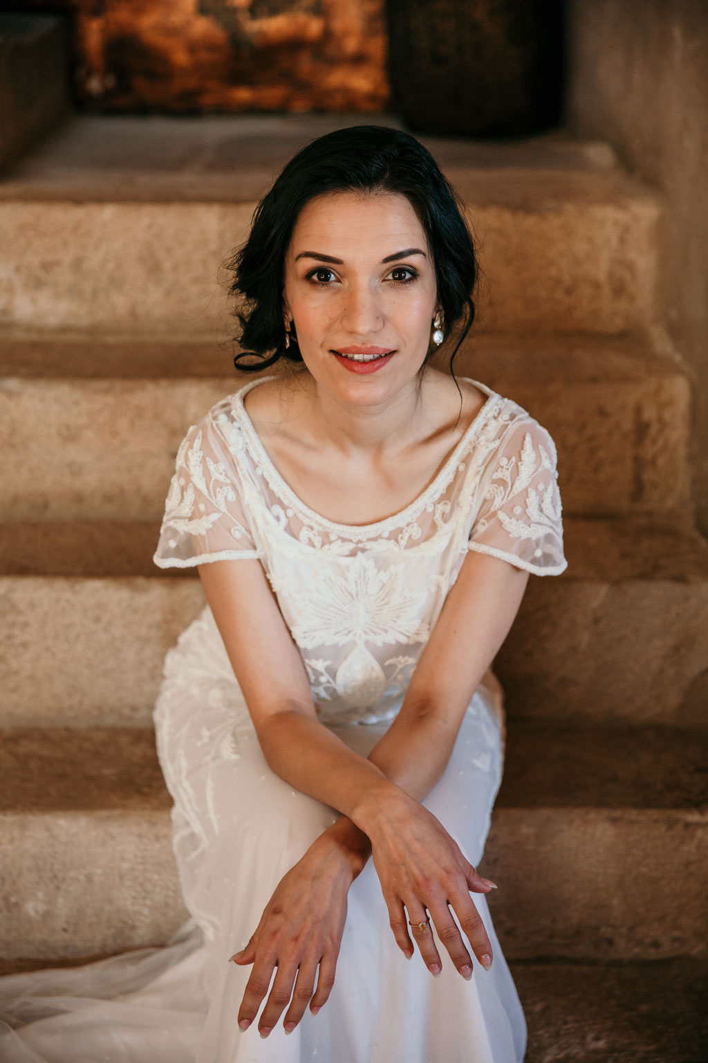 Anja pavlova sitzt auf Steintreppe mit Hochzeitskleid in Finka in Barcelona 