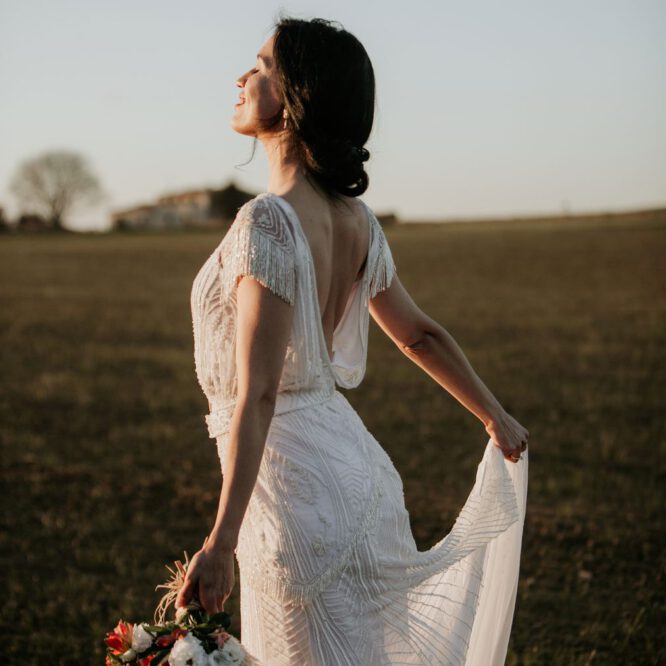 Anja pavlova trägt ein brautkleid von Tilda knopf aus berlin und trägt einen Brautstrauß beim Sonnenuntergang in Barcelona