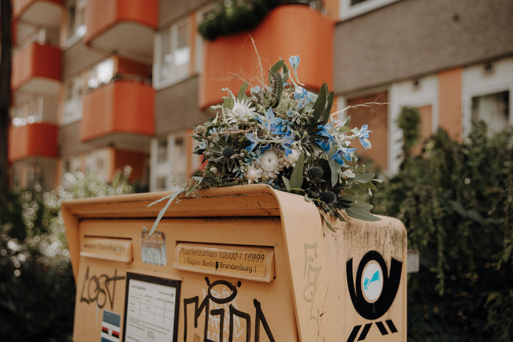 Brautstrauß Blumenstrauß blaue Blüten Standesamt Villa Kogge heiraten 2022 standesamtliche Trauung mit Eltern Hochzeitsfotografie und Hochzeitsfotograf Berlin Paarfotos Siemenssteg Paar Arm in Arm Briefkasten typisch Berlin Hipsterhochzeit Tinywedding