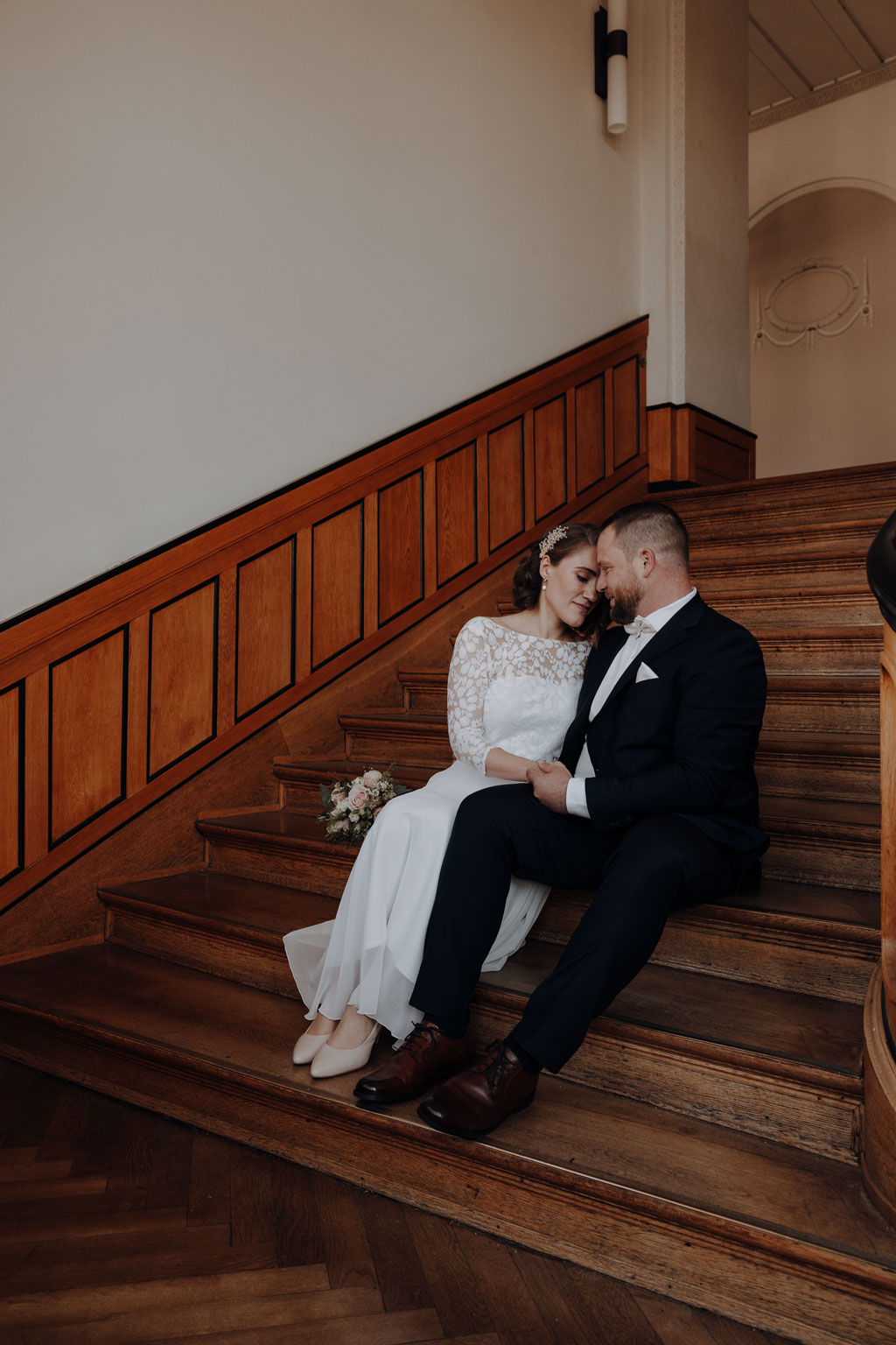 Hochzeit im Standesamt berlin treptow köpenick denkmalgüschtztes rathaus beliebte Filmkulisse für film heiraten Standesamt trauung in berlin Portraits auf Holztreppe Wendeltreppe Paarfotos in berlin hochzeitsfotograf berlin 