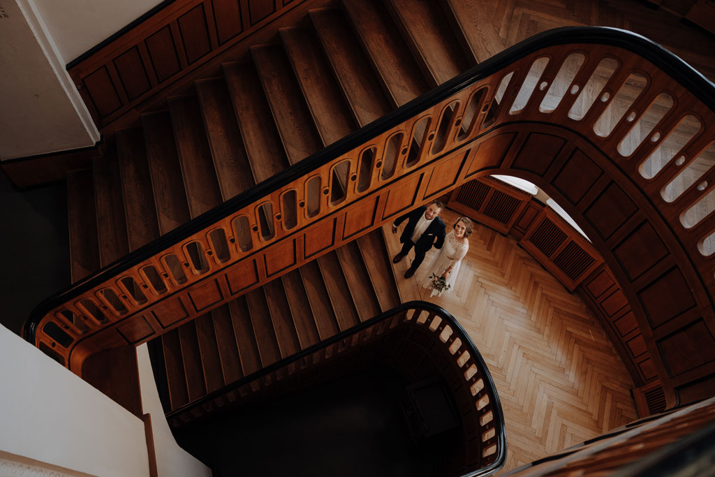 Hochzeit im Standesamt berlin treptow köpenick denkmalgüschtztes rathaus beliebte Filmkulisse für film heiraten Standesamt trauung in berlin Portraits auf Holztreppe Wendeltreppe Paarfotos in berlin hochzeitsfotograf berlin