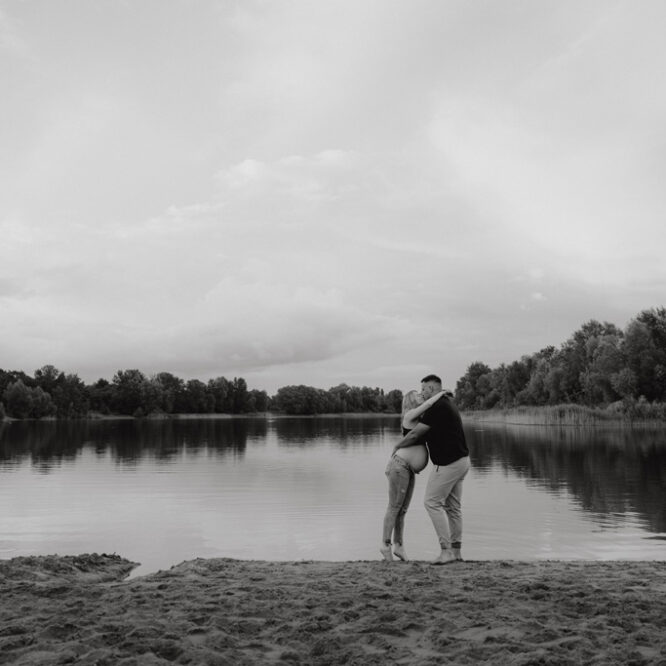 Babybauchfotos in berlin mit der Berliner Fotografin für Kinderfotografie Maria Brussig Lensofbeauty. fotos am See. Fotoshooting Babybauch im grünen. Wasser im Hintergrund. Paarfotos zusammen am See.