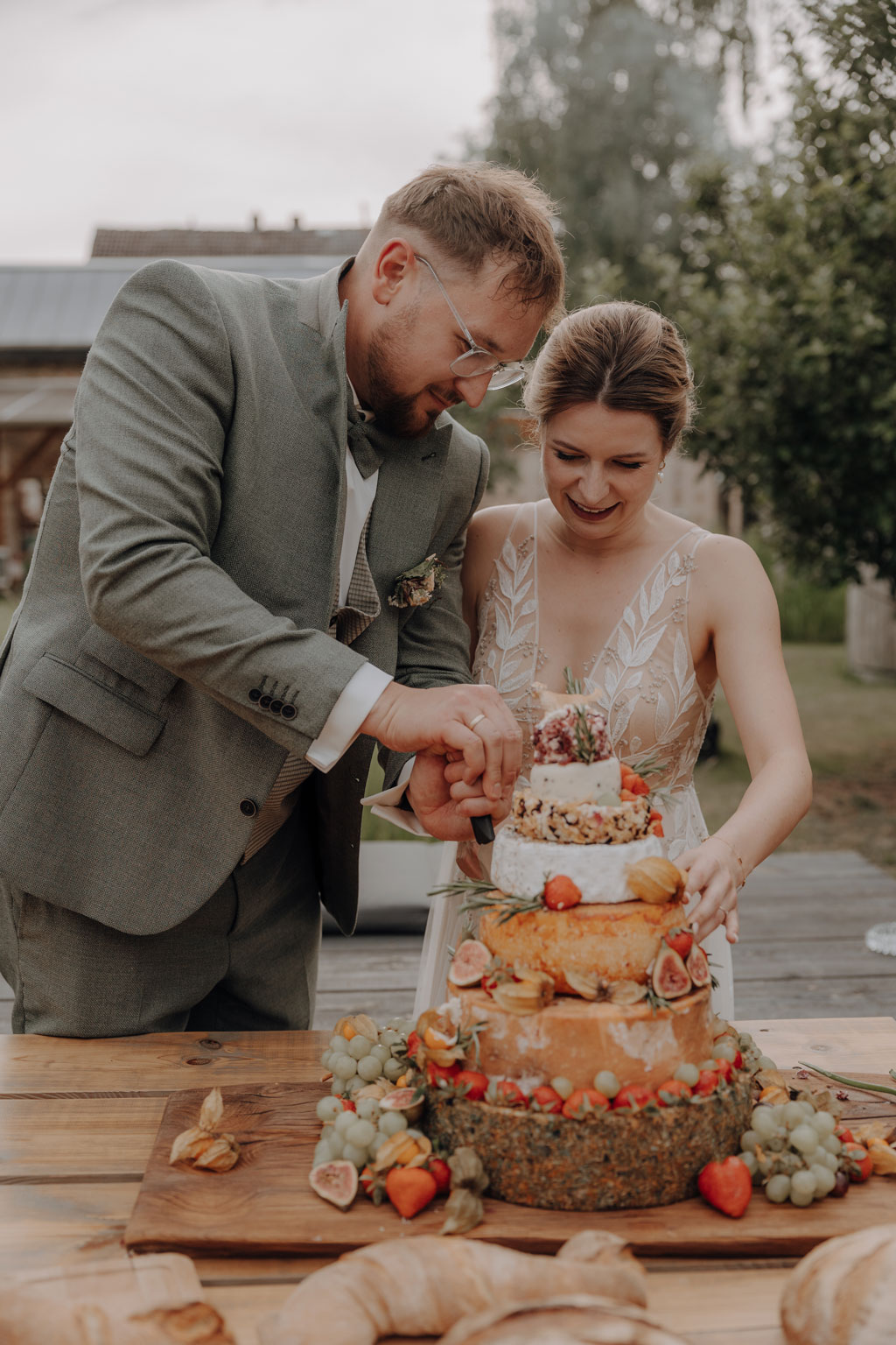 hochzeitsfotograf im farmhouse in wandlitz in Brandenburg bei berlin hochzeitslocation in der Natur festivalwedding Festivalhochzeit Fotograf fotografiert hochzeit trauung freie trauung waldkapelle kuchen käse anschnitt hochzeitstorte